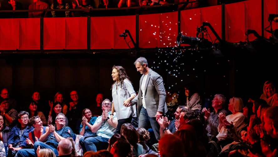 Minnie Driver holding hands with a man on stage @sohoplace, being showered in white confetti.